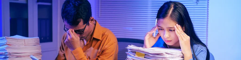 Image of a businessman and woman are stressed working on documents