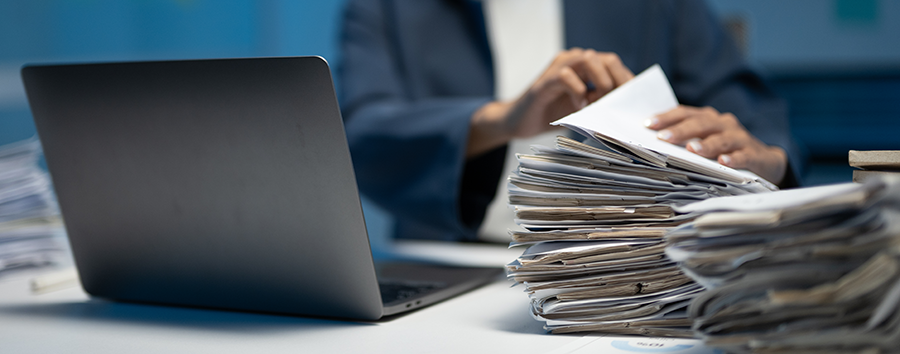 Person with computer going through stacks of paperwork