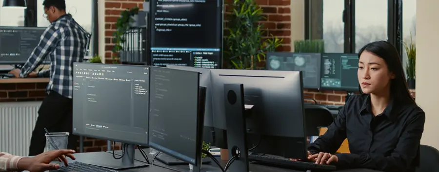 Female Cyber Security Specialist Sat at Desk Multiple Screens
